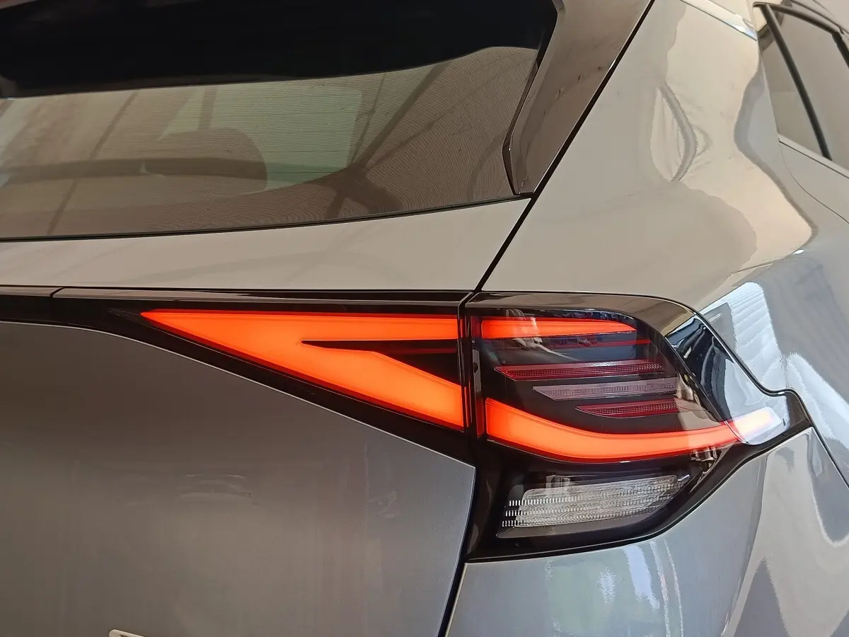 Feu arrière droit allumé sur KIA Sportage gris clair, vue rapprochée du coin arrière du véhicule.