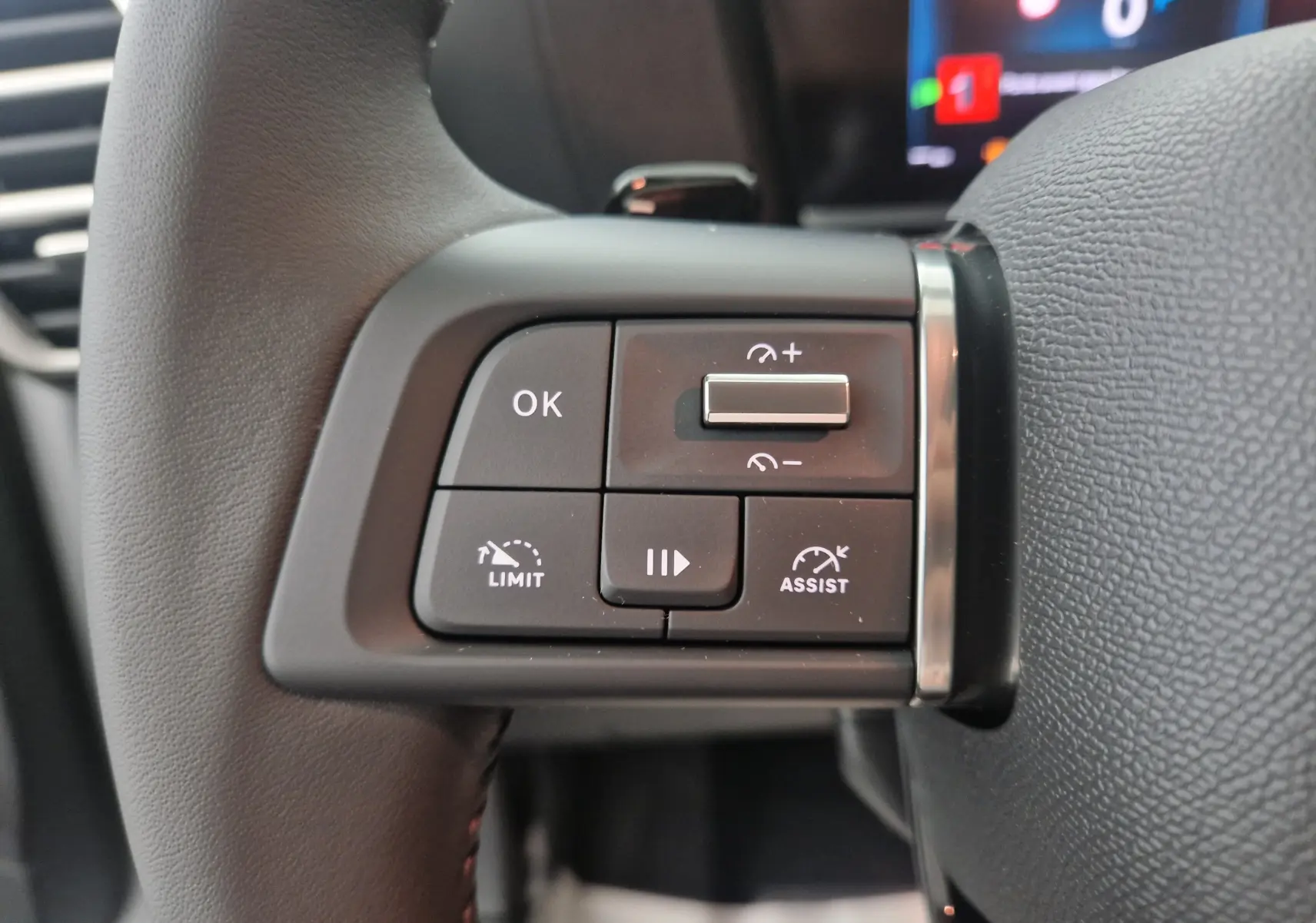 Gros plan sur les commandes au volant côté gauche du Citroën C4 blanc Okenite 2025, boutons de régulateur et assistant de conduite.