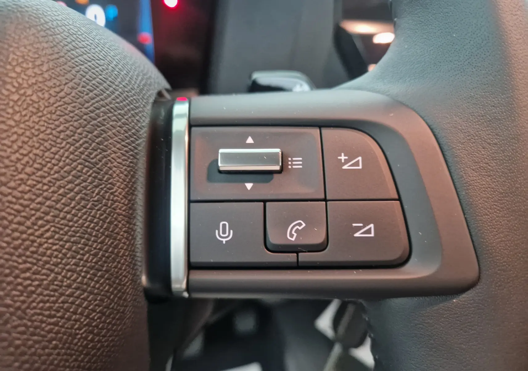 Gros plan sur les commandes du volant à gauche d'une Citroën C4 Blanc Okenite 2025, boutons de volume et téléphone visibles.