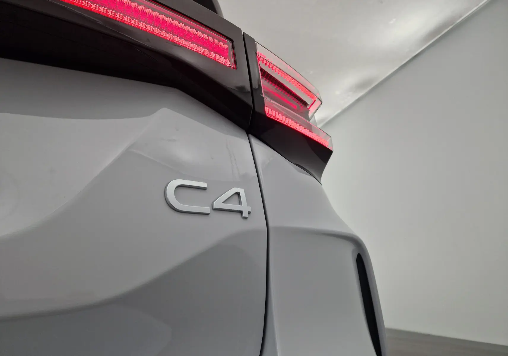 Gros plan sur l'arrière blanc Okenite d'une Citroën C4 2025 avec feux arrière LED allumés et logo C4 visible.