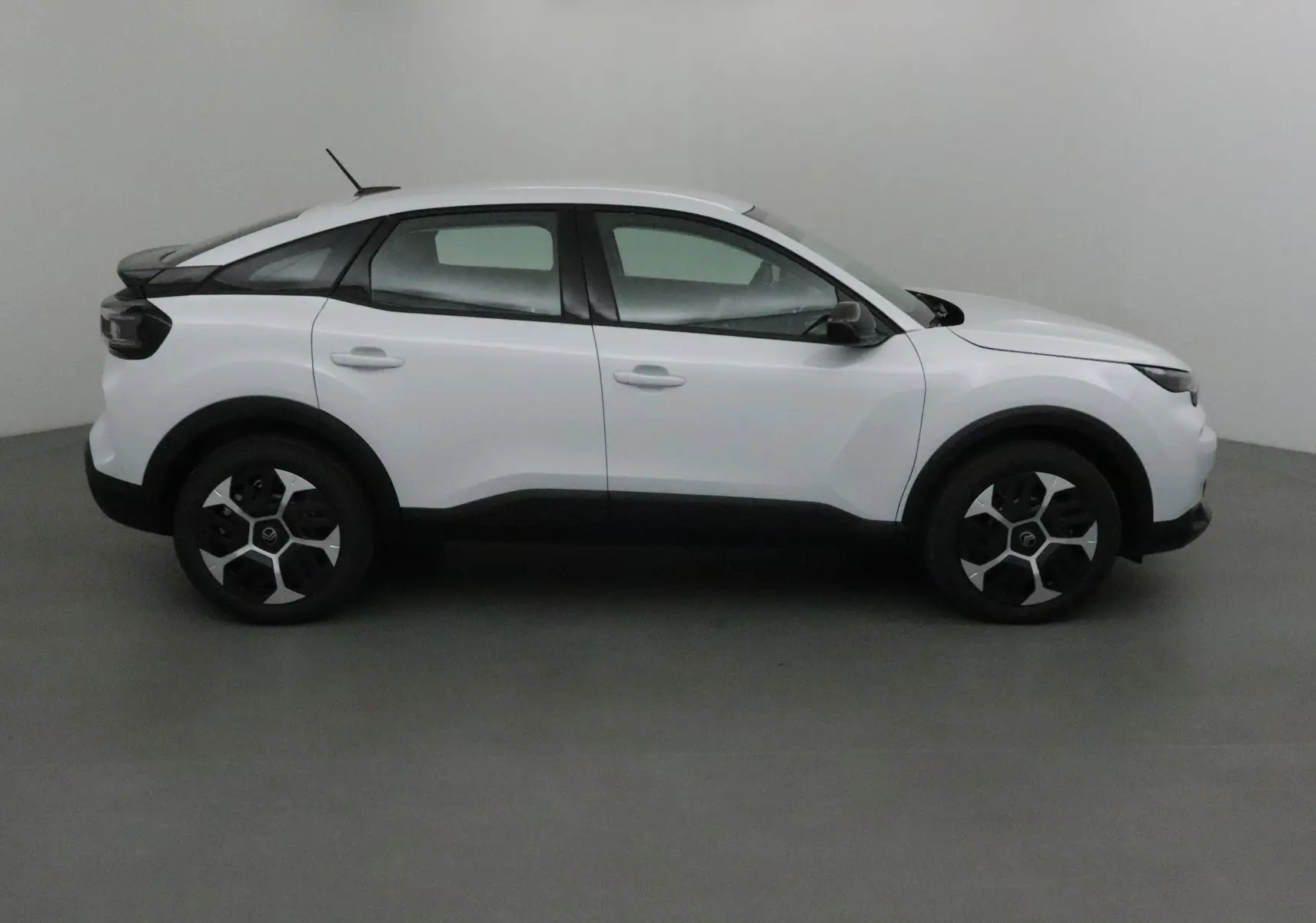 Profil côté gauche d'une Citroën C4 blanc okenite 2025 avec jantes noires et toit noir contrasté.