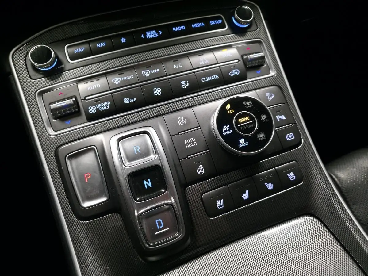 Vue rapprochée de la console centrale noire du Hyundai Santa Fé 2023 avec commandes de climatisation et boîte auto boutons poussoirs.