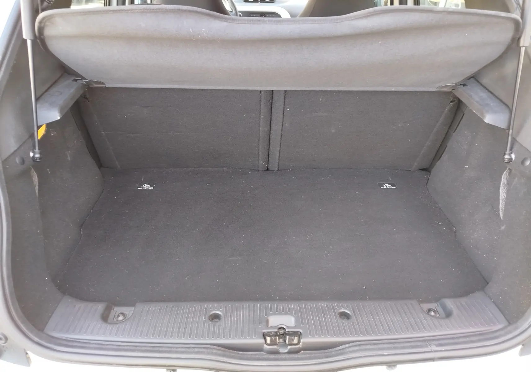 Coffre ouvert vu de l'arrière d'une Renault Twingo blanc cristal 2016, montrant un espace de chargement vide et propre.