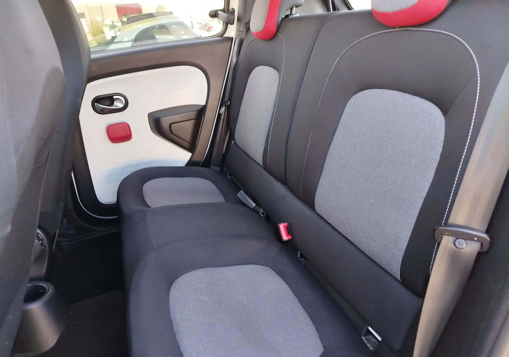 Vue intérieure de la banquette arrière de la Renault Twingo 2016, sièges gris et noir avec appuie-têtes rouges.