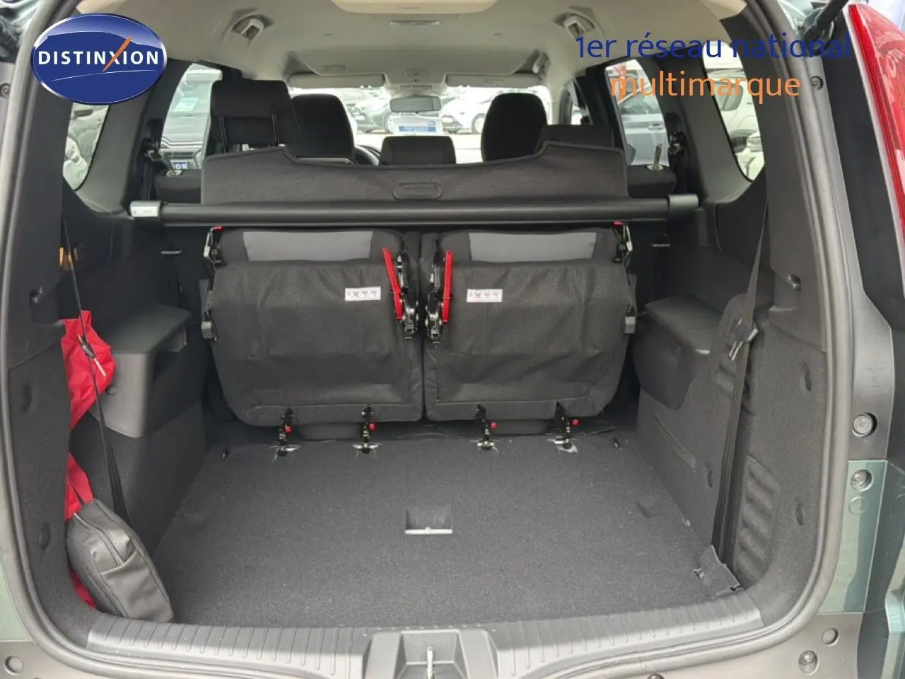 Vue arrière du coffre ouvert d'un Dacia Jogger vert cèdre métal, montrant les sièges rabattus et l'espace de chargement.