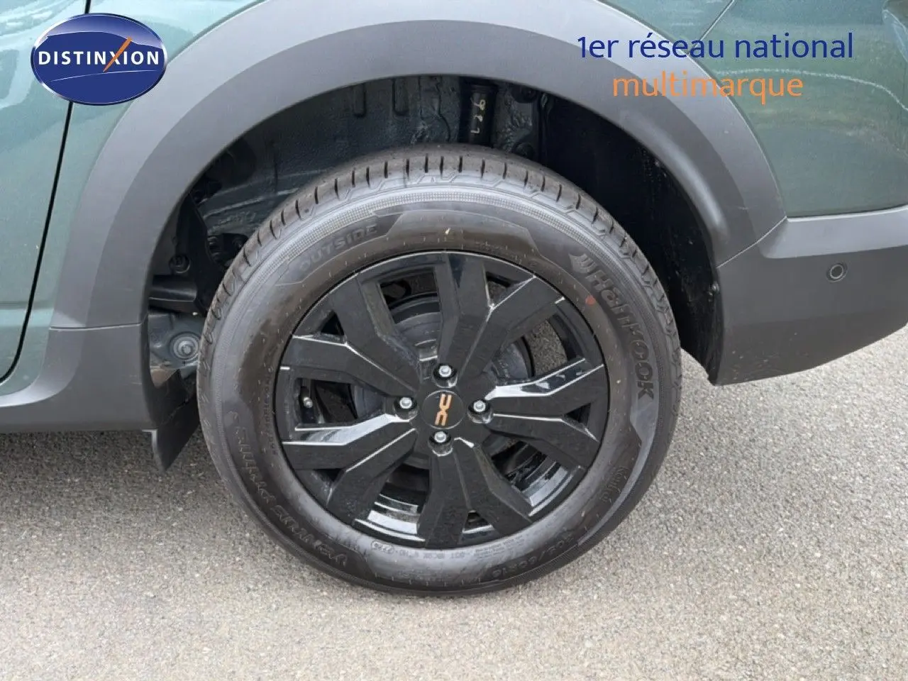 Gros plan sur la roue arrière droite noire avec jante noire brillante du Dacia Jogger vert cèdre métal.