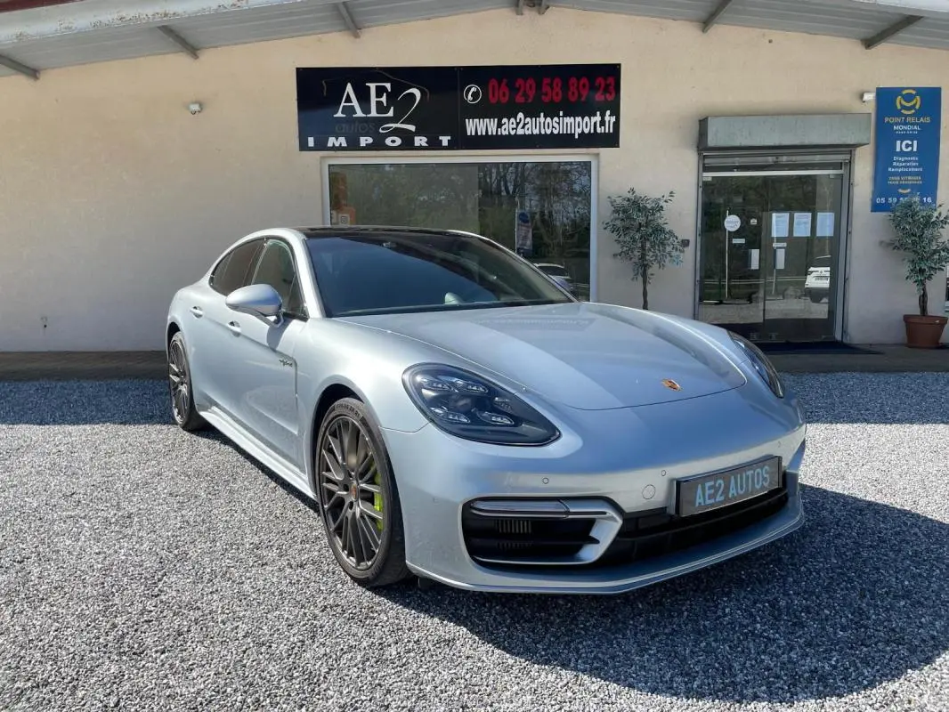 Porsche Panamera 4 V6 Hybrid gris vue 3/4 avant droit, jantes noires et étriers de frein verts visibles.