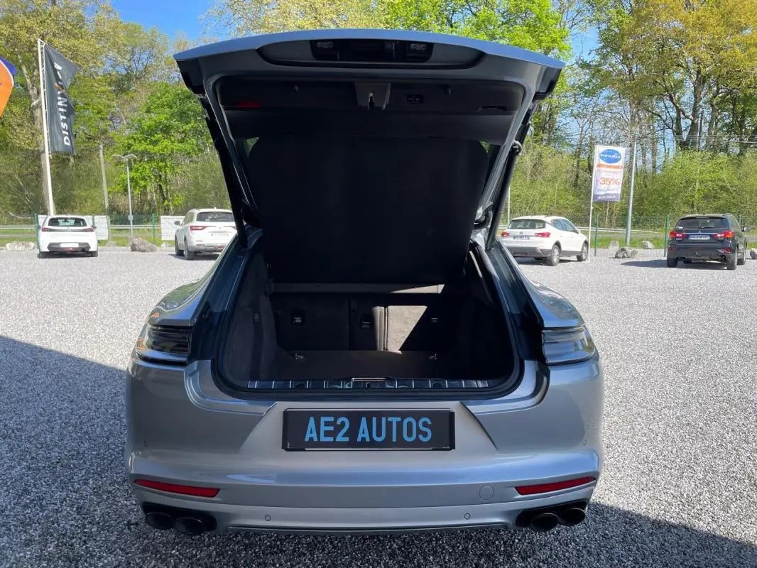 Vue arrière d'une Porsche Panamera 4 V6 3.0 Hybrid gris 2022 avec coffre ouvert et double sortie d'échappement noire.