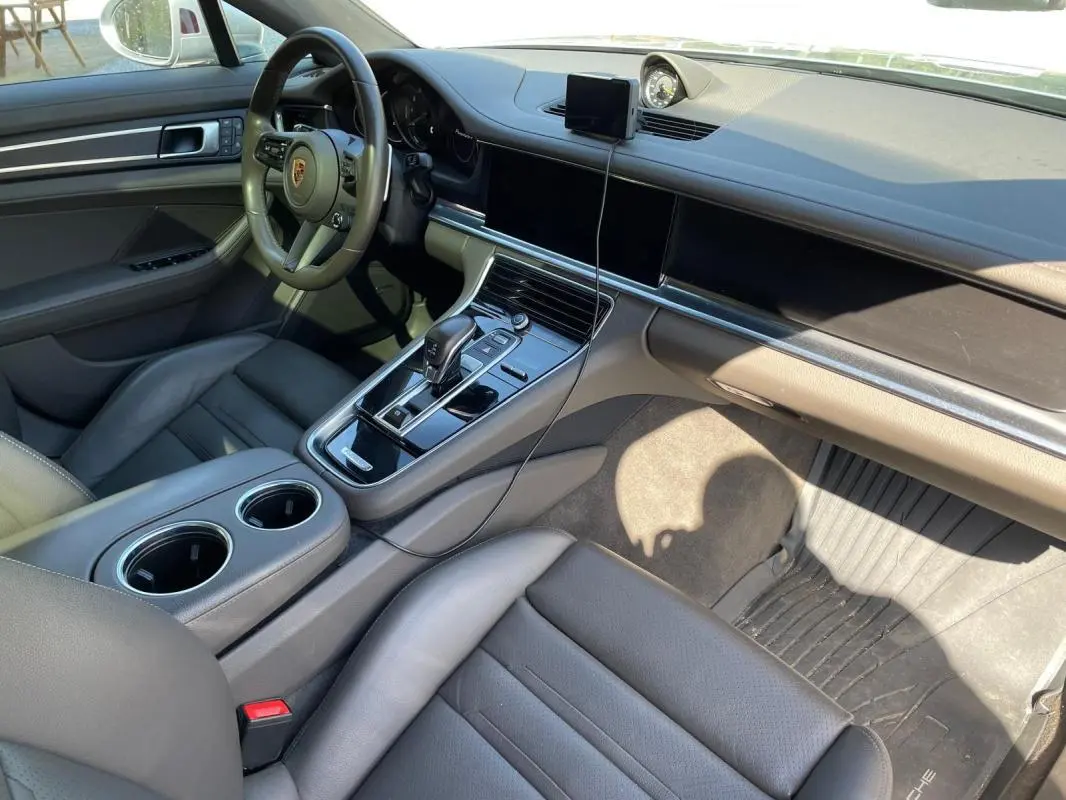 Vue intérieure côté conducteur du Porsche Panamera gris, mettant en valeur le tableau de bord moderne et la console centrale.