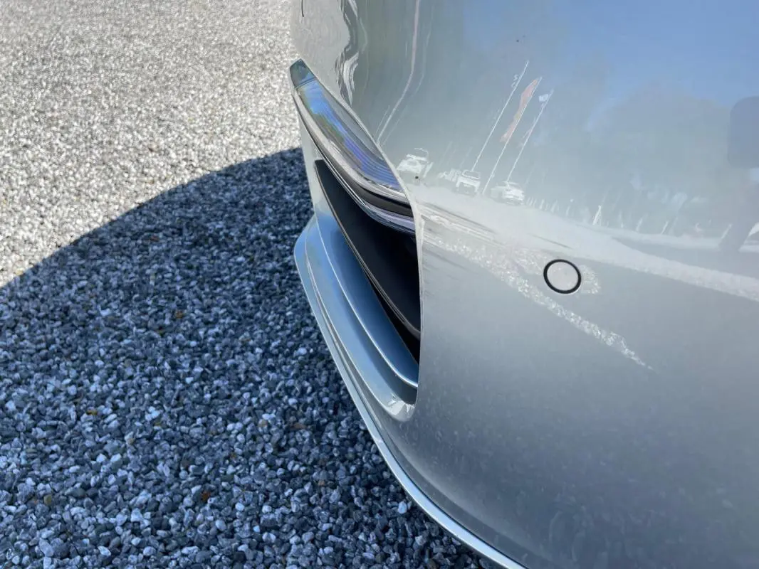 Gros plan sur l'avant droit gris d'une Porsche Panamera 4 V6 Hybrid 2022, mettant en valeur la prise d'air et le capteur de stationnement.