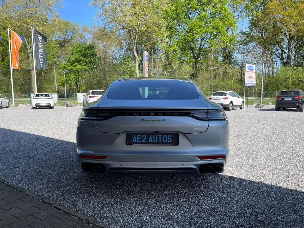 Vue arrière d'une Porsche Panamera 4 grise 2022, avec feux arrière reliés et double sortie d'échappement noire.