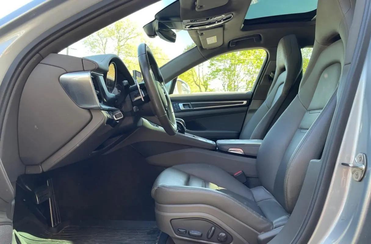Vue intérieure côté conducteur de la Porsche Panamera 4 V6 Hybrid 2022 avec sièges cuir gris et toit ouvrant panoramique.