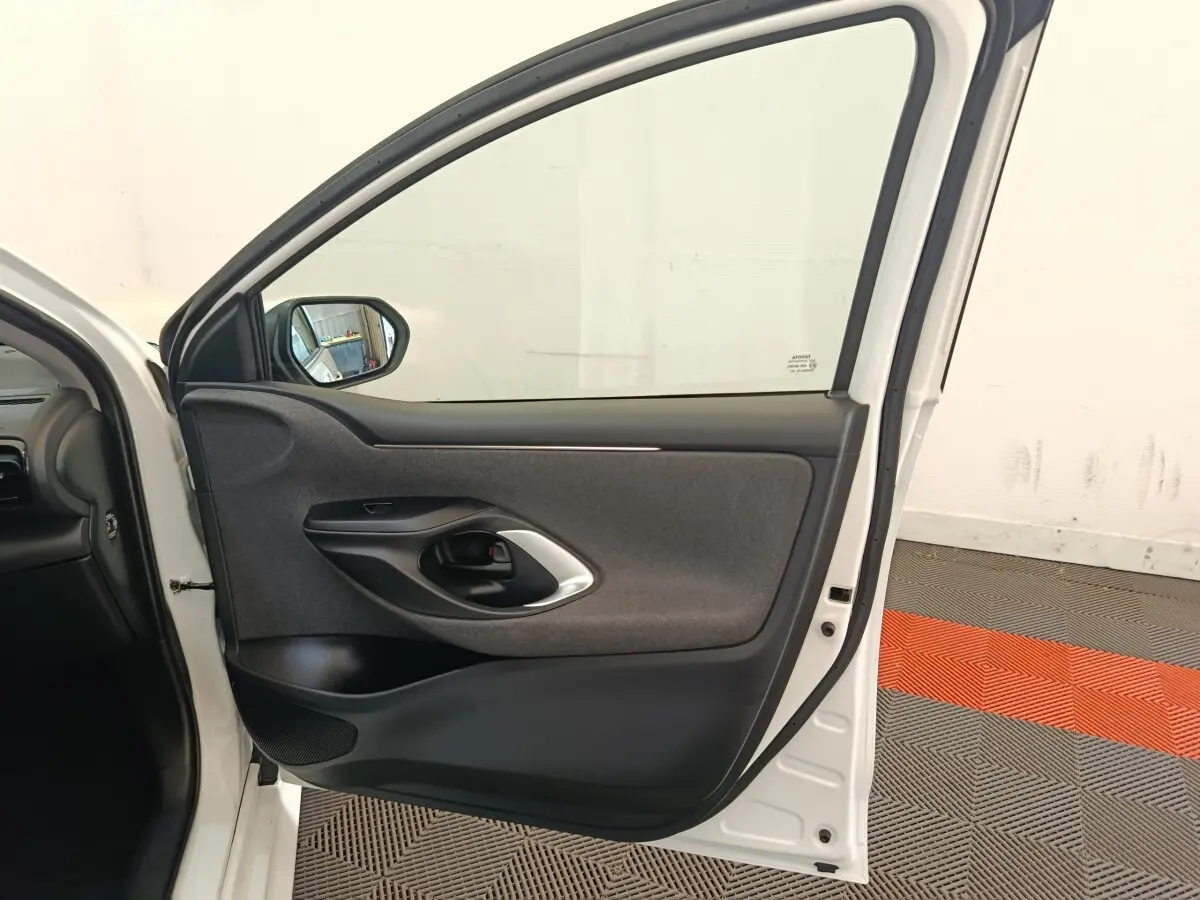 Vue intérieure de la porte arrière droite blanche d'une Toyota Yaris Hybride 2022, avec garniture grise et poignée noire.