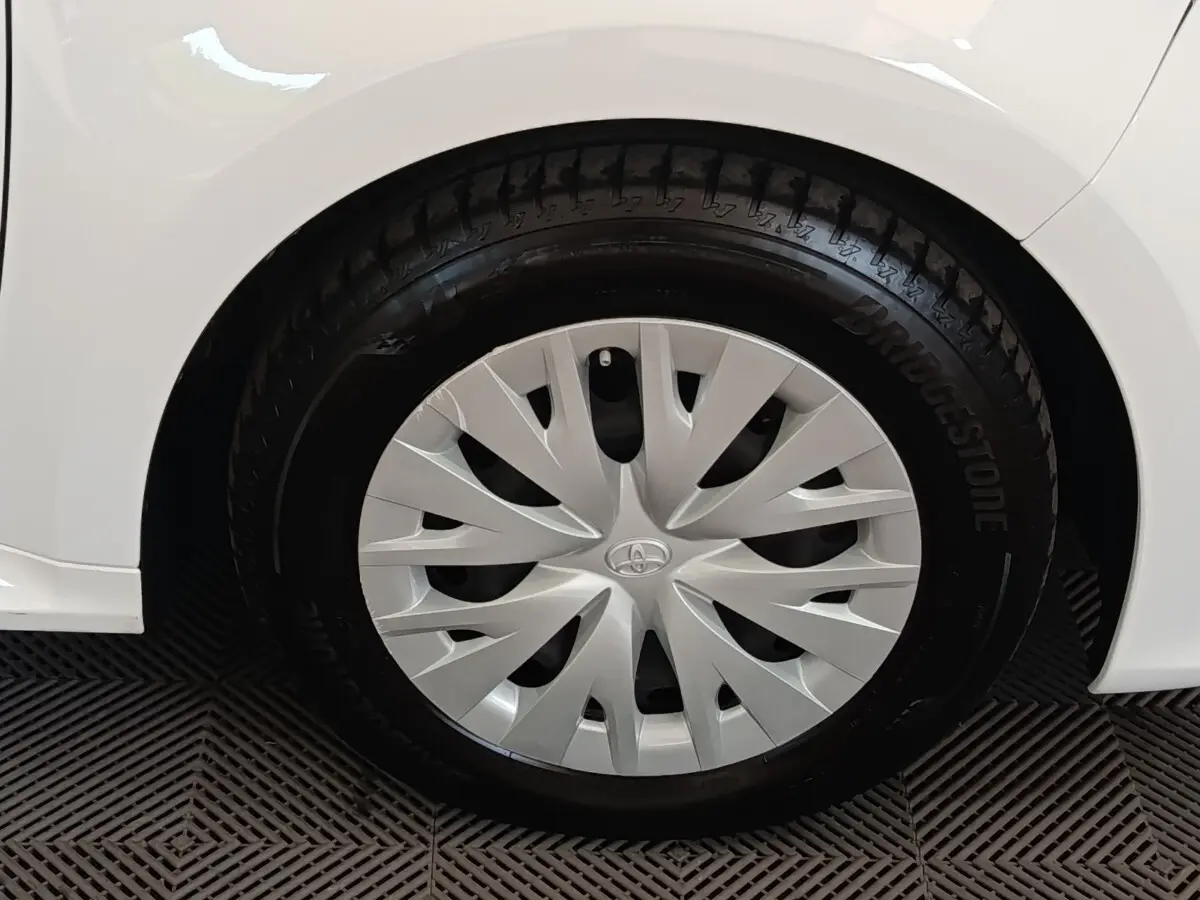 Gros plan sur la roue arrière droite blanche d’une Toyota Yaris hybride 2022 avec enjoliveur argenté à motifs dynamiques.