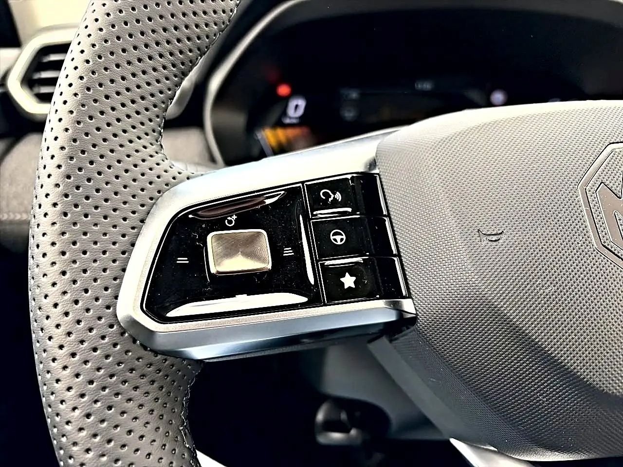 Gros plan sur la partie gauche du volant perforé gris avec commandes multifonctions du MG MOTOR ZS hybride 2026.