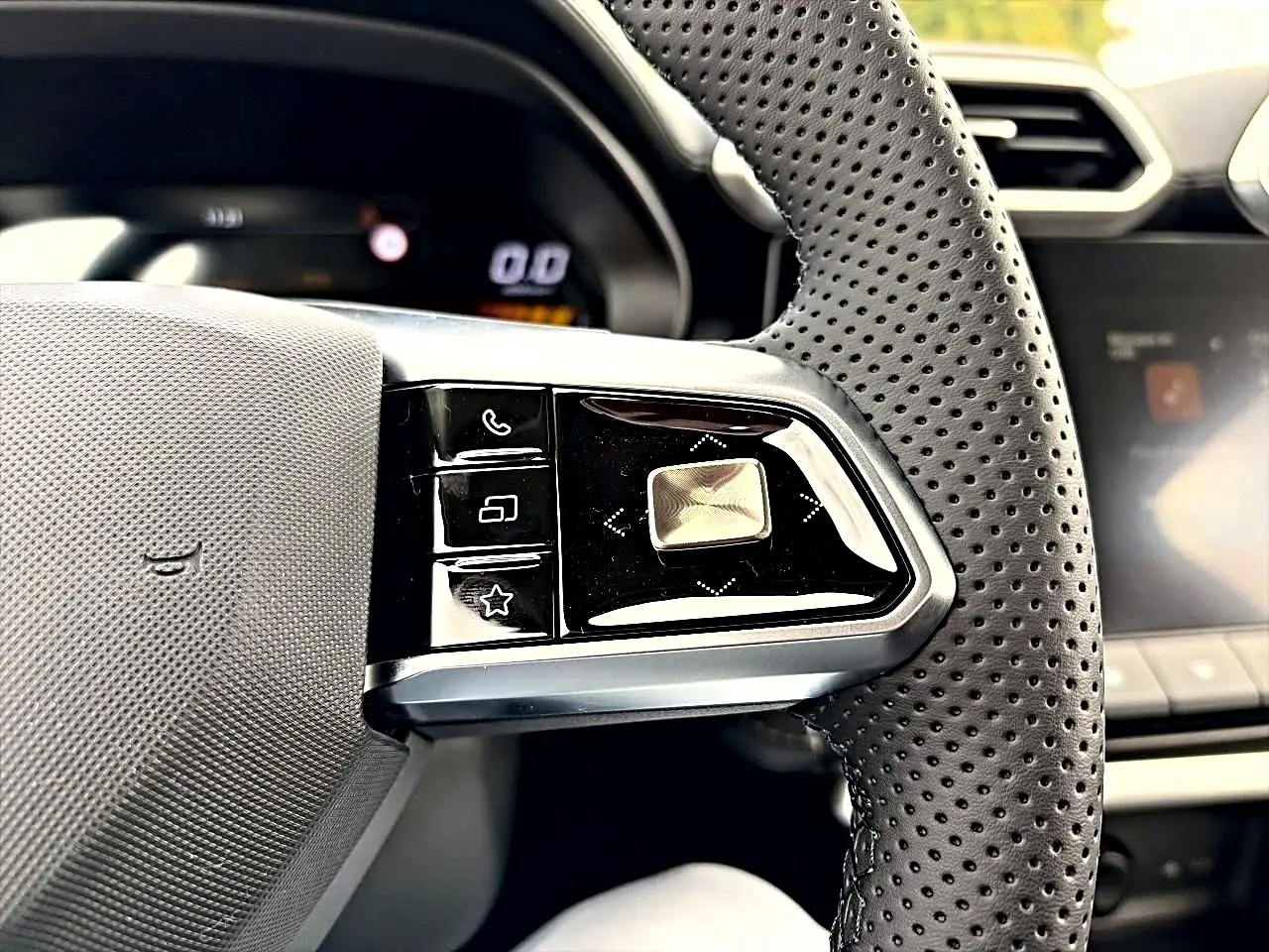 Gros plan sur la partie gauche du volant perforé noir du MG ZS 1.5 hybrid 2026 avec commandes multifonctions.