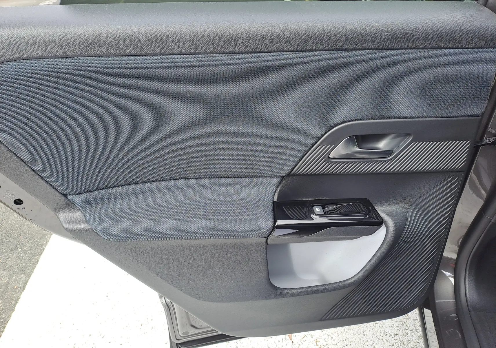 Gros plan sur la porte arrière droite du Citroën C5 Aircross gris platinium, avec insert tissu bleu et détails noirs texturés.