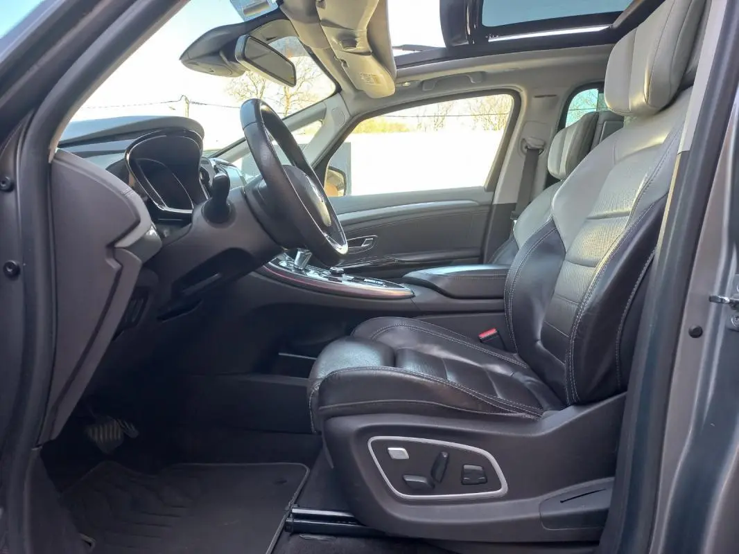 Intérieur côté conducteur du Renault Espace gris 2017, sièges cuir noirs et toit panoramique ouvert.