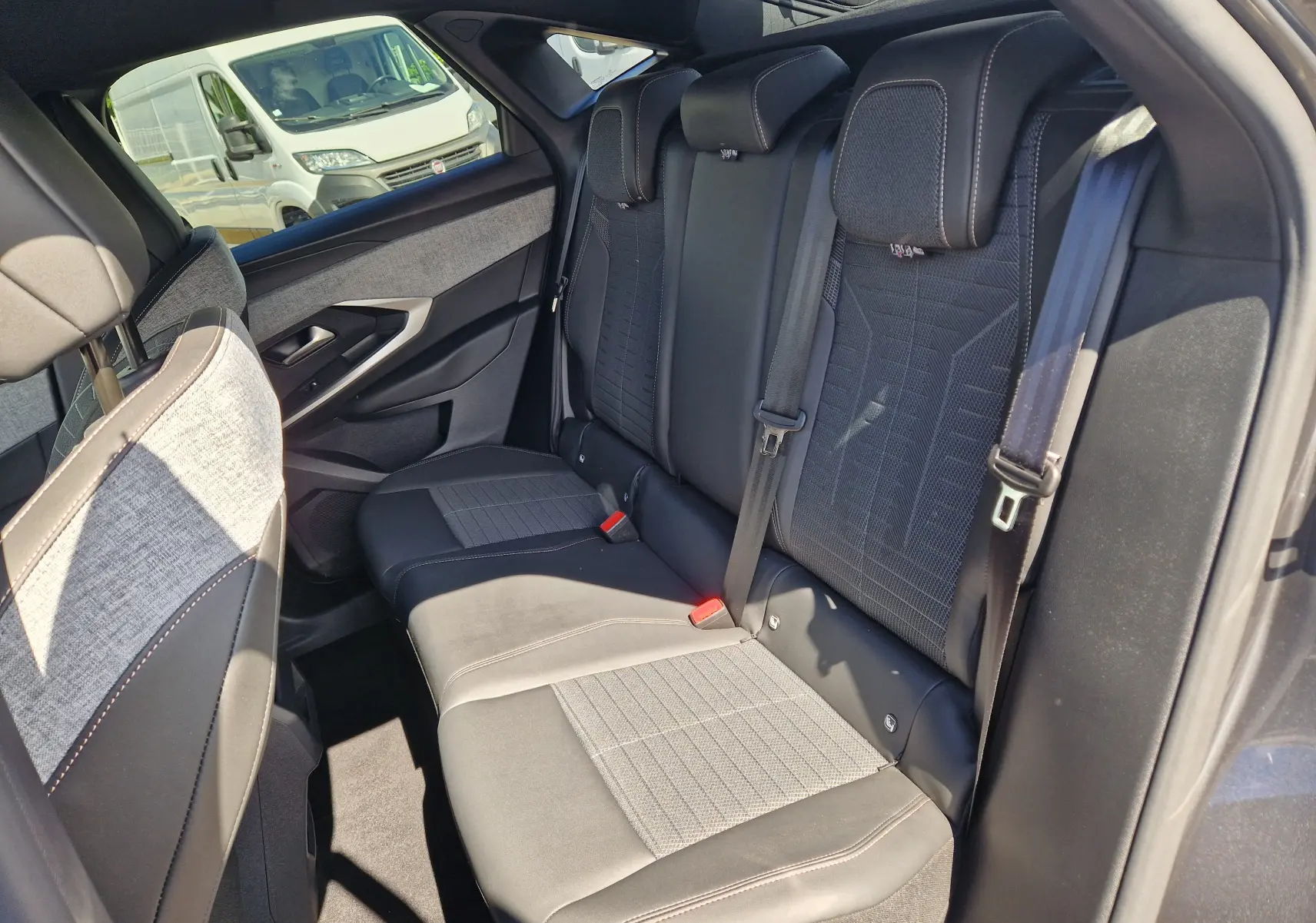 Vue intérieure côté arrière droit du Peugeot 3008 1.2 Hybrid 145 Allure, sièges tissu et cuir gris avec surpiqûres contrastées.