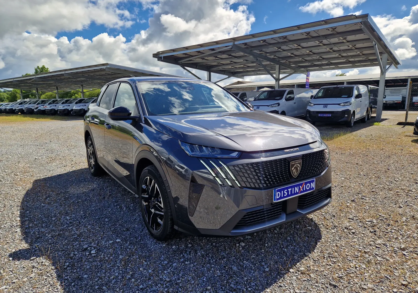 Vue 3/4 avant droite du Peugeot 3008 gris titane 2026 avec calandre distinctive et jantes noires brillantes.