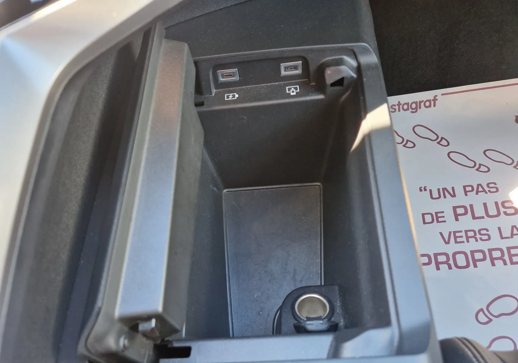 Vue rapprochée de la console centrale ouverte du Peugeot 3008 gris titane, montrant ports USB et prise 12V.