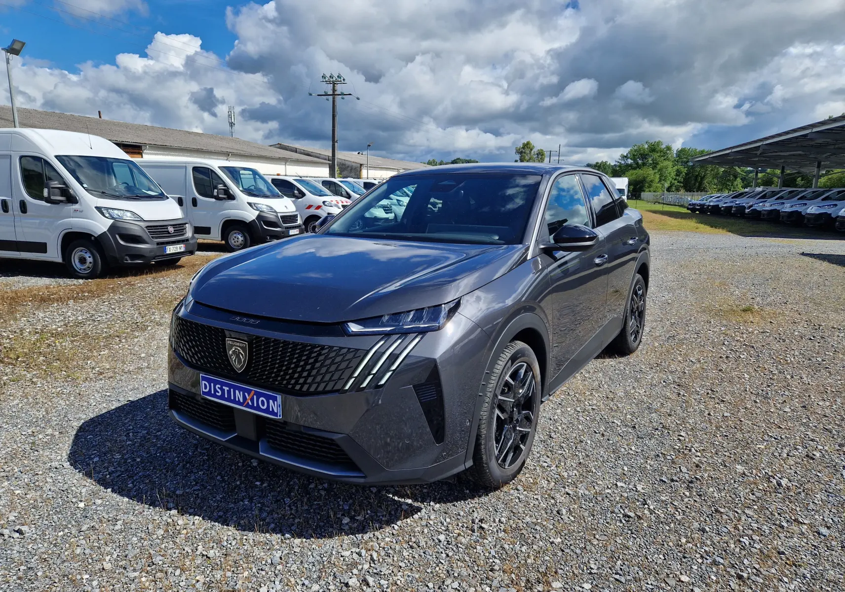 Peugeot 3008 gris titane en 3/4 avant droit sur un parking extérieur, avec calandre noire et jantes noires.