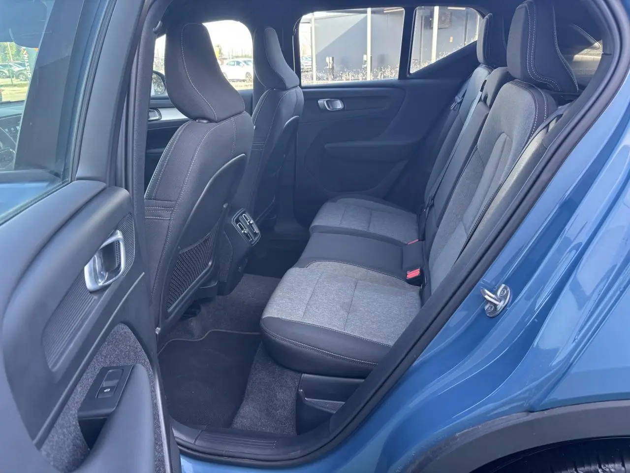 Vue côté gauche de l’arrière du Volvo XC40 Fjord Blue avec sièges bi-matière gris et noir et aérateurs centraux.