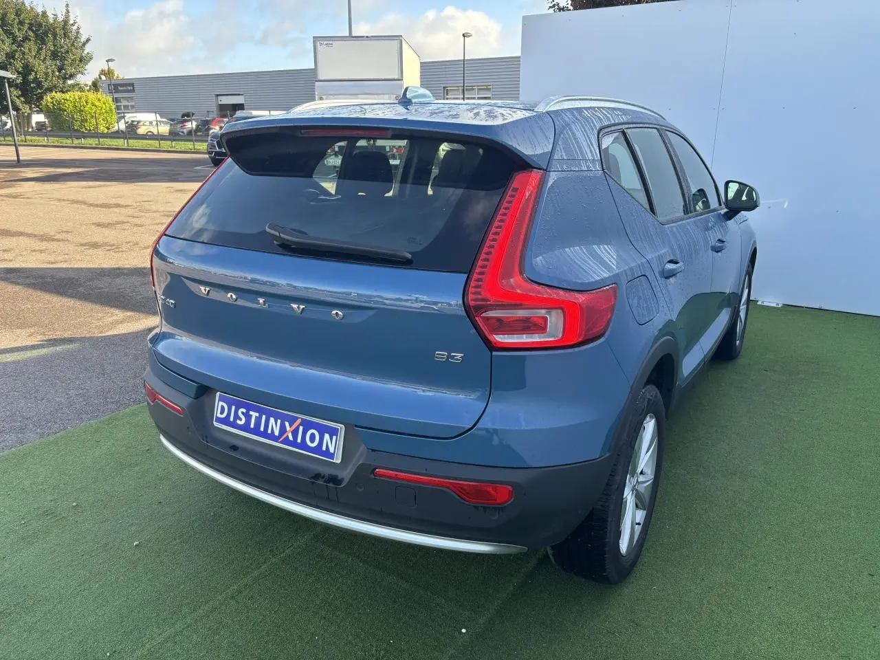 Vue 3/4 arrière droite d'un Volvo XC40 Fjord Blue avec feux arrière en L et jantes alliage 18 pouces.