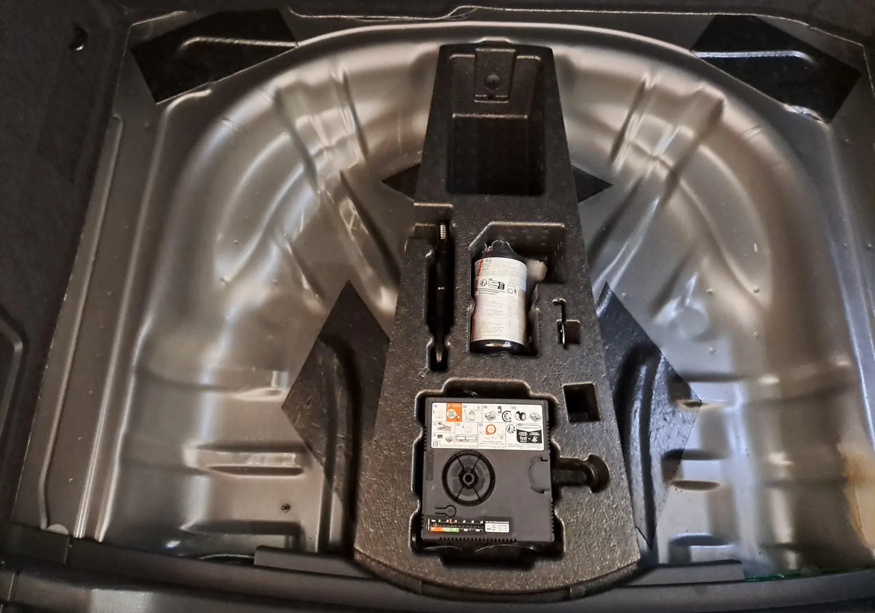 Vue plongeante sur le compartiment de roue de secours du Skoda Karoq 2025 gris graphite, avec kit de réparation intégré.