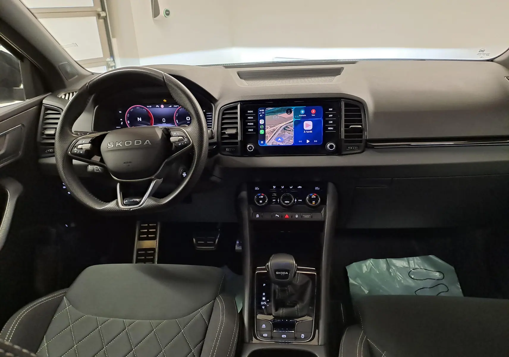Vue intérieure frontale du tableau de bord et volant SKODA KAROQ 2.0 TDI gris graphite avec écran tactile et levier de vitesses automatique.