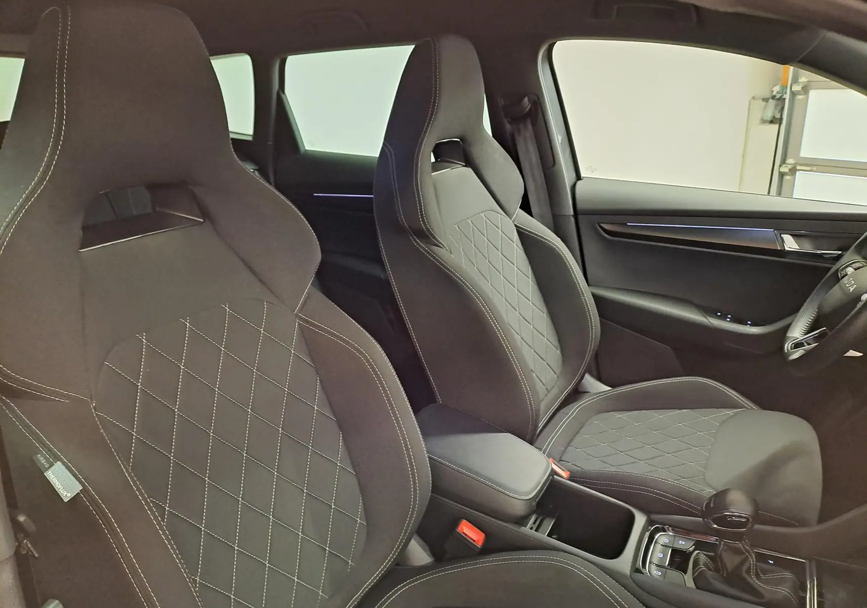 Vue intérieure des sièges avant sport noirs avec surpiqûres blanches du Skoda Karoq 2.0 TDI 150 DSG7 Sportline 2025.
