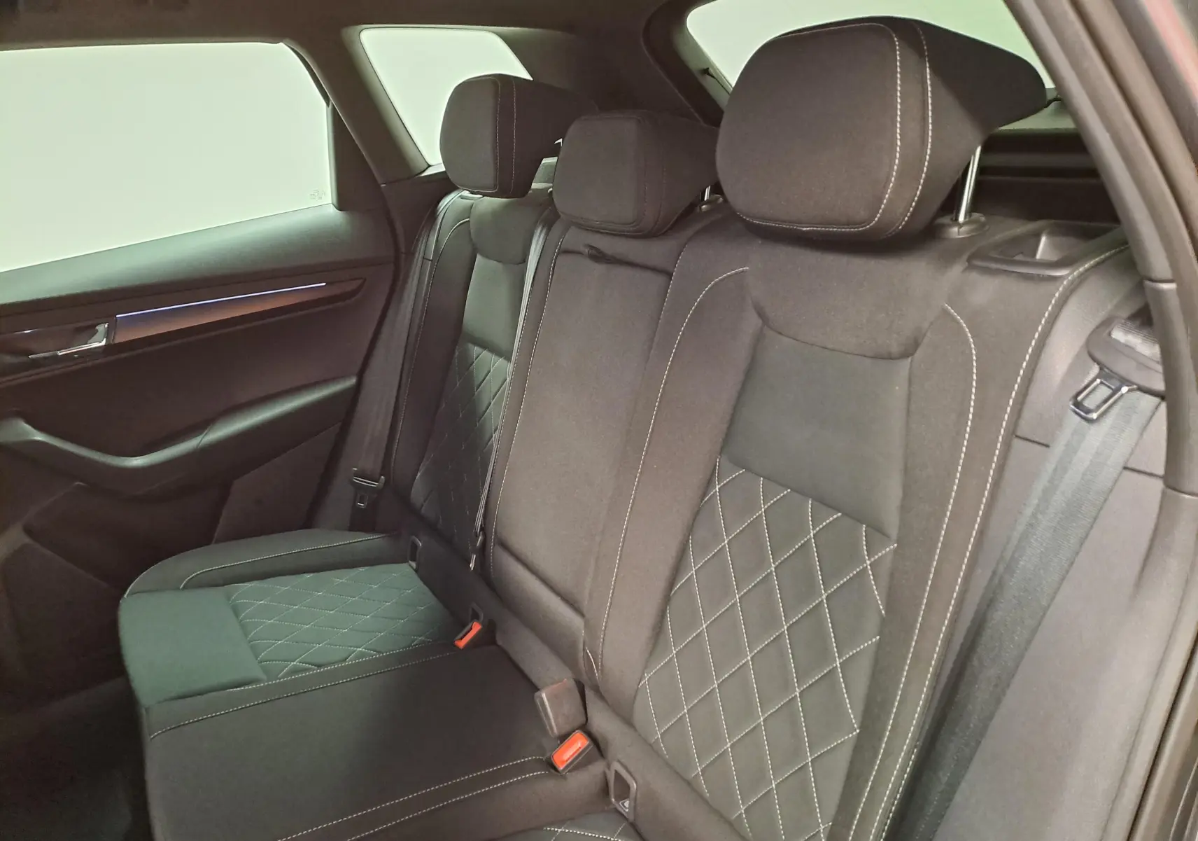 Vue intérieure côté droit des sièges arrière en tissu noir avec surpiqûres blanches du Skoda Karoq 2025 gris graphite.