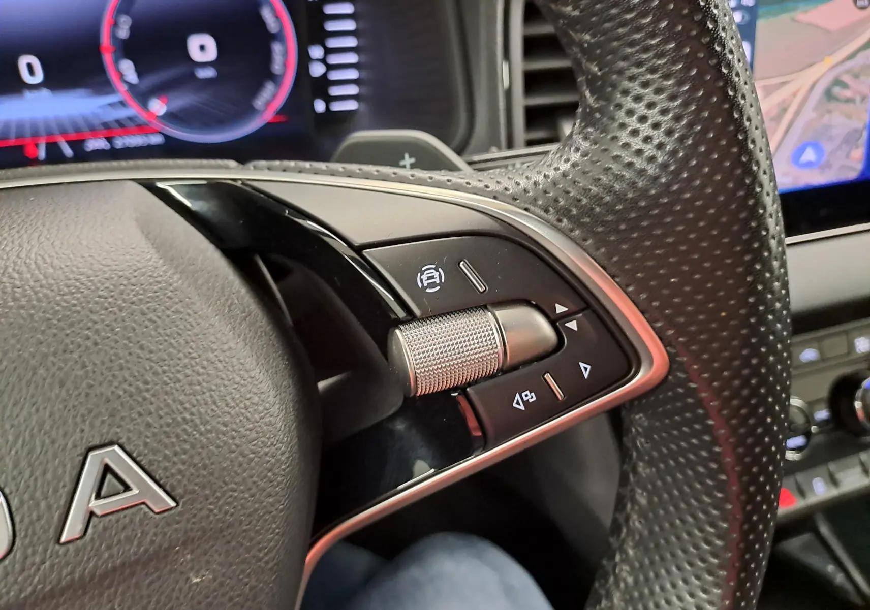 Gros plan sur les commandes du volant perforé côté gauche du Skoda Karoq gris graphite 2025 avec tableau de bord numérique.