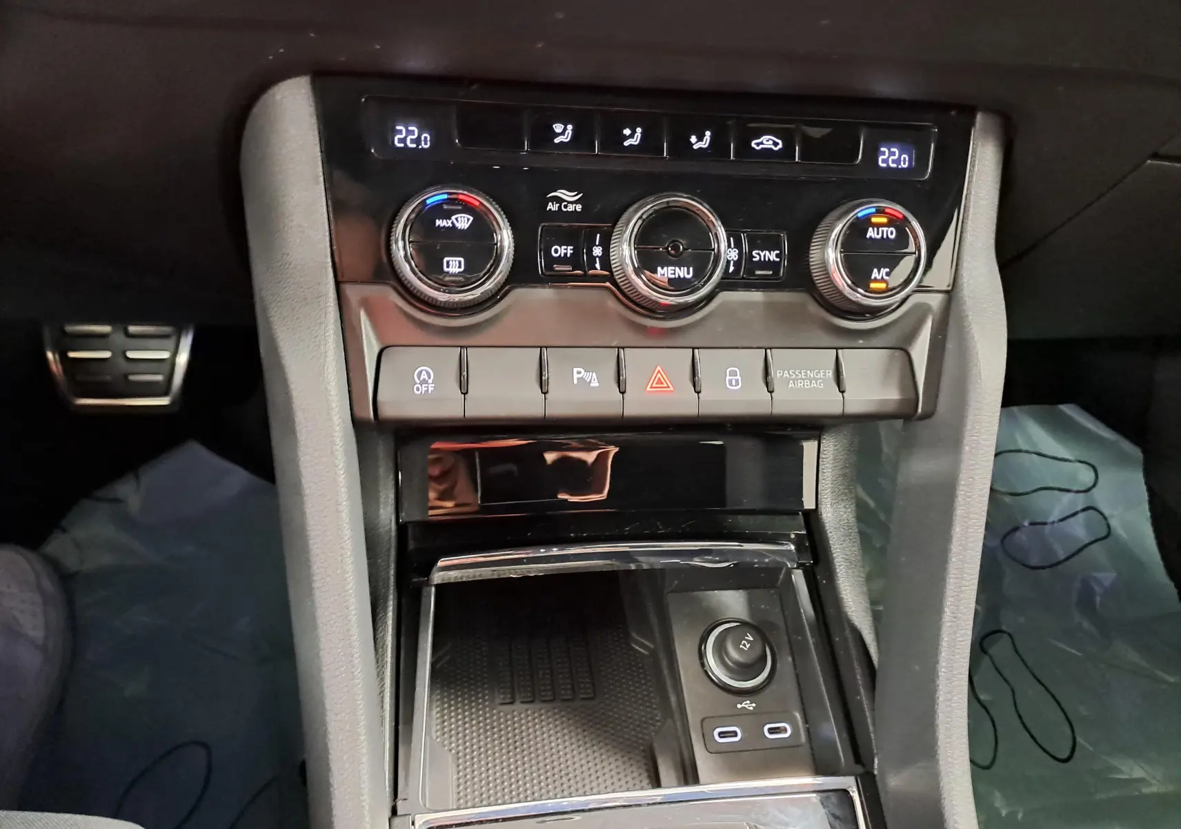 Vue intérieure centrée sur la console centrale du Skoda Karoq gris graphite, avec commandes climatisation et ports USB visibles.