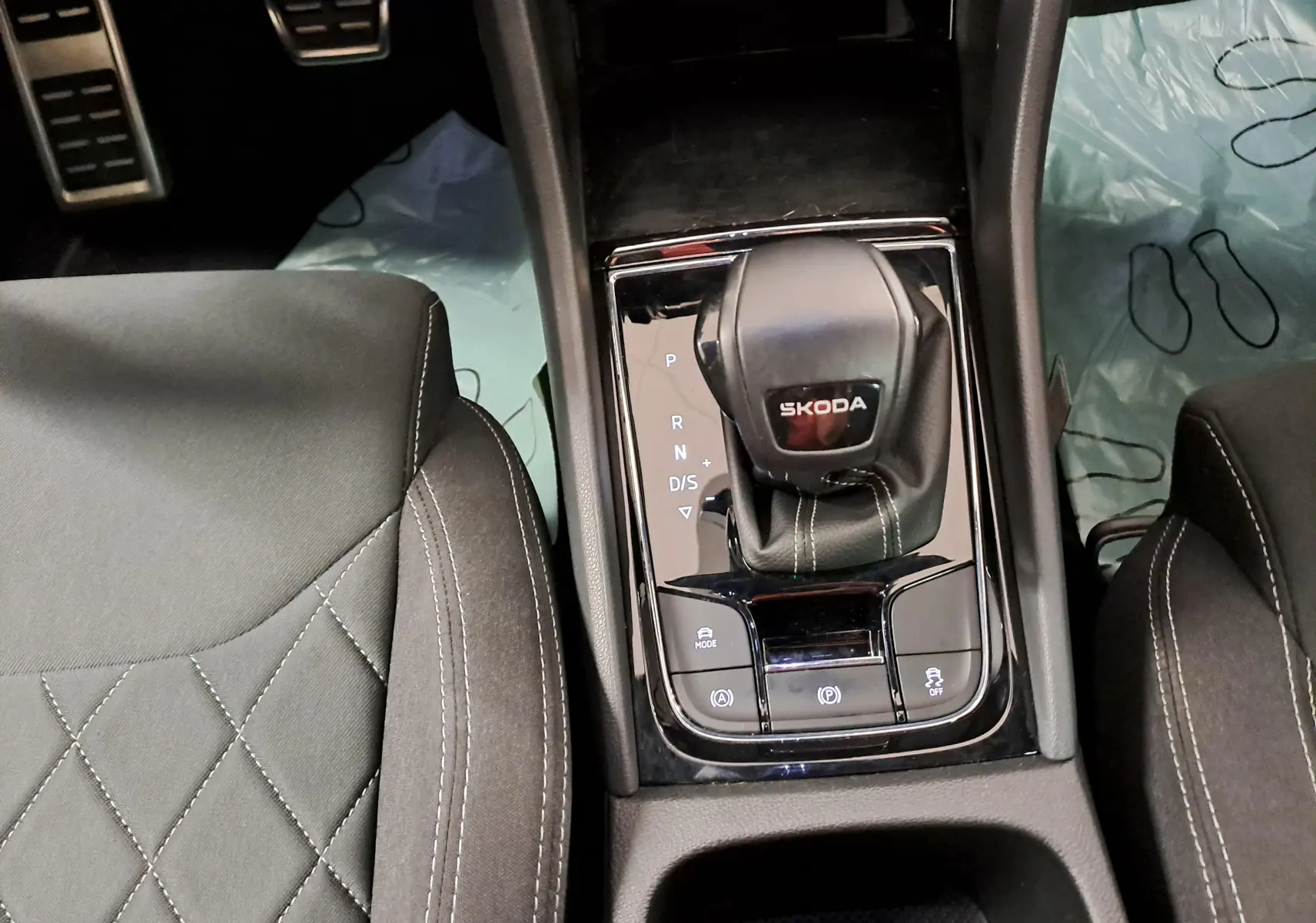 Vue rapprochée de la console centrale du Skoda Karoq 2025 avec levier de vitesses DSG et sièges en tissu gris.