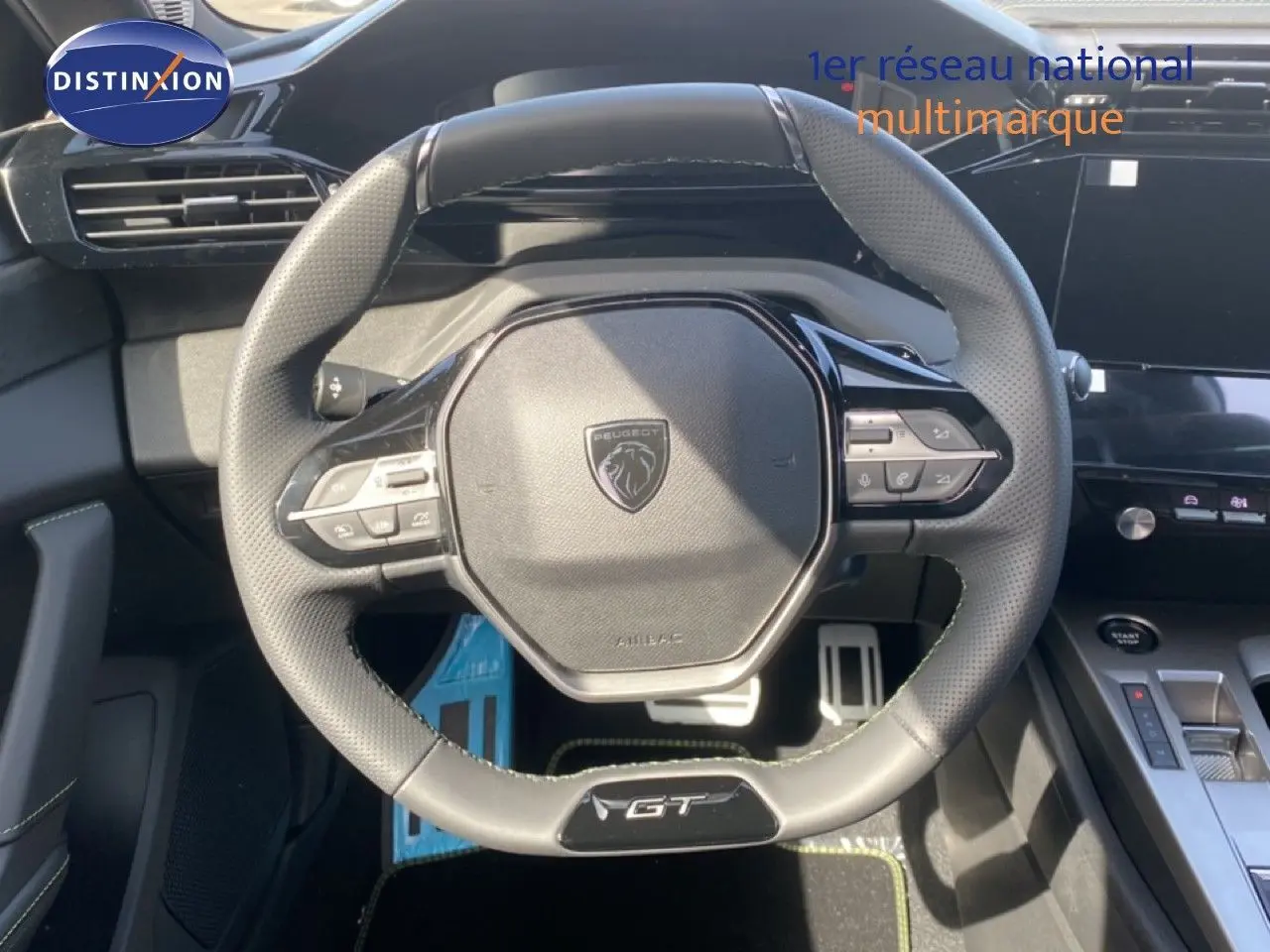 Vue rapprochée du volant cuir noir GT de la Peugeot 308 Hybrid 145ch, avec commandes intégrées et tableau de bord moderne.