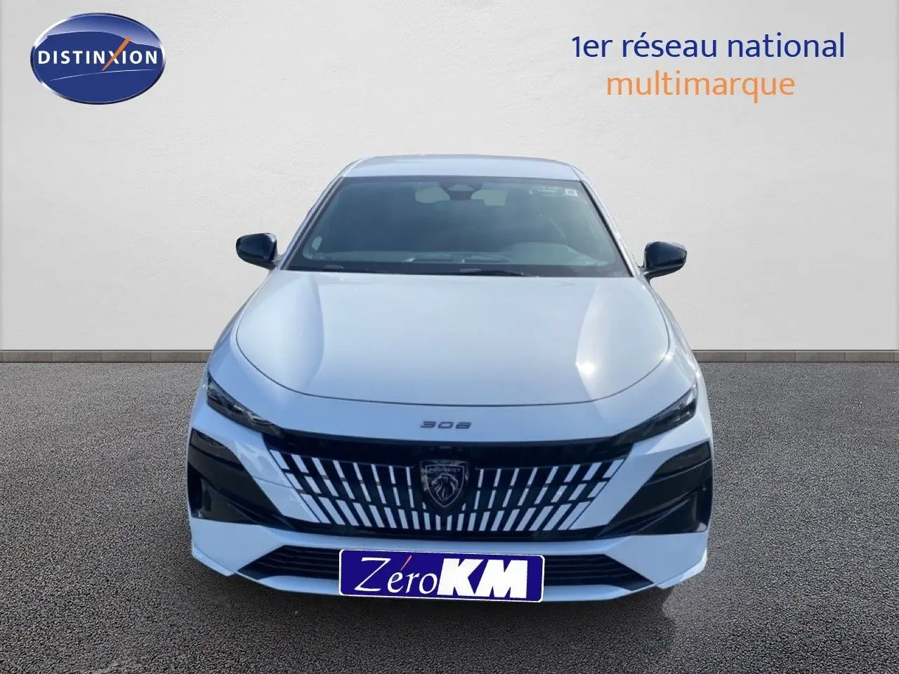 Vue frontale d'une Peugeot 308 Hybrid 145ch GT blanche Okenite Metal avec calandre distinctive et phares fins.