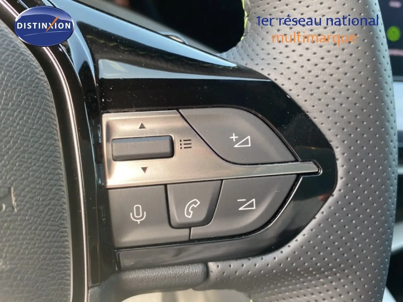 Gros plan sur les commandes de volume et téléphone du volant perforé d’une Peugeot 308 Hybrid blanche.