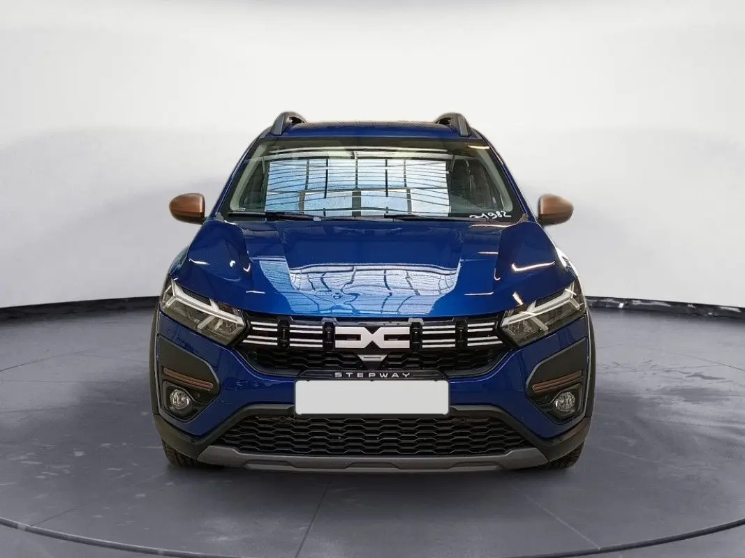 Vue frontale d'une Dacia Sandero Stepway TCE 90 bleu Iron avec calandre noire et détails bronze sur les rétroviseurs.