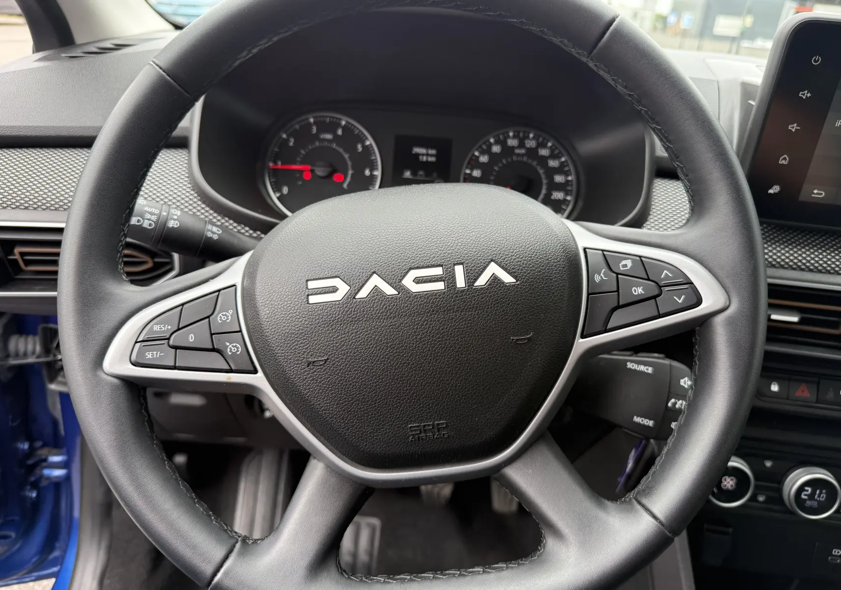 Vue rapprochée du volant noir de la Dacia Sandero Stepway 2025, avec commandes intégrées et tableau de bord en arrière-plan.