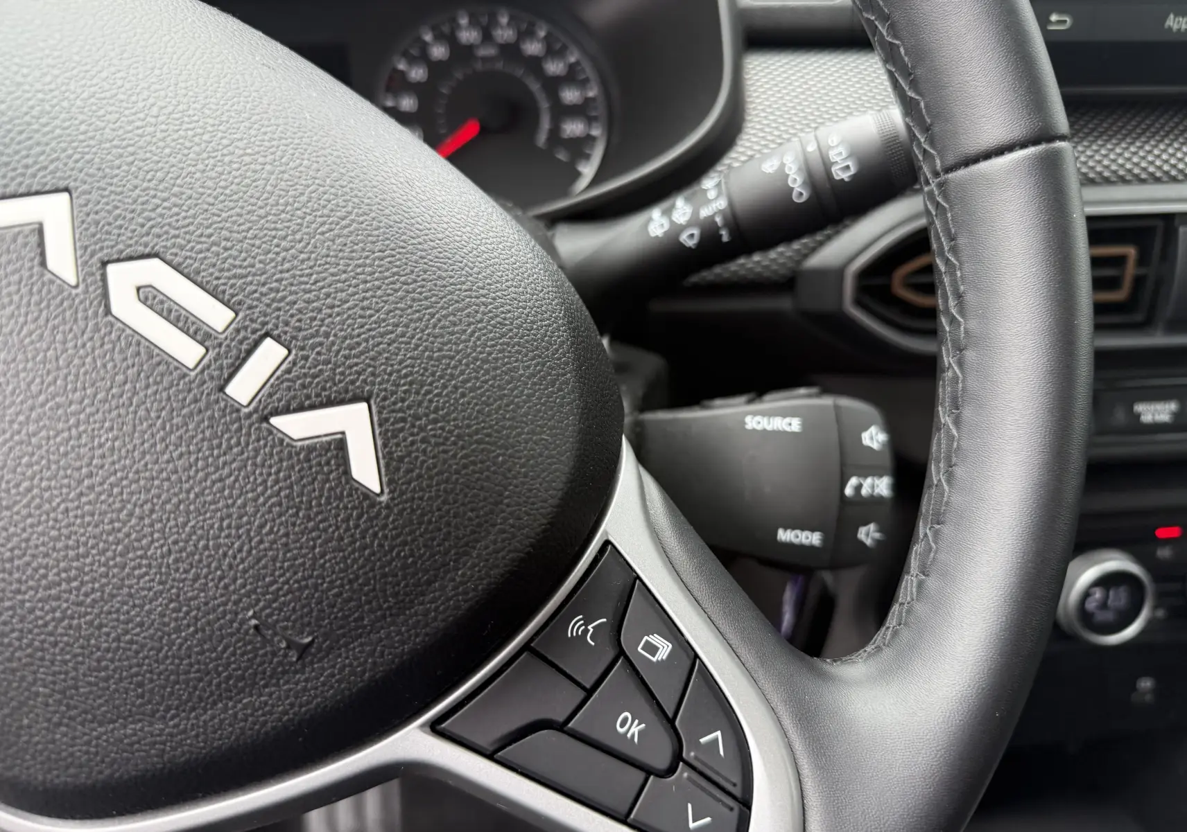 Gros plan sur le volant noir du Dacia Sandero Stepway 2025 avec commandes intégrées et tableau de bord partiellement visible.