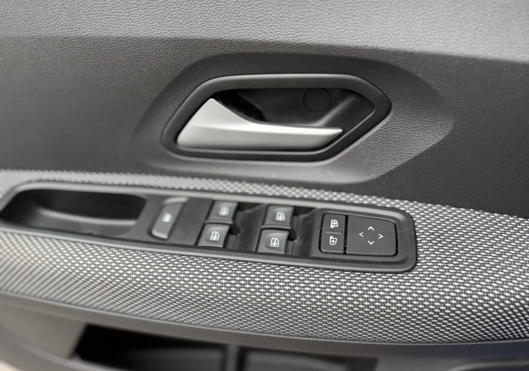Gros plan sur la poignée intérieure et les commandes des vitres côté conducteur de la Dacia Sandero Stepway 2025, finition Expression.