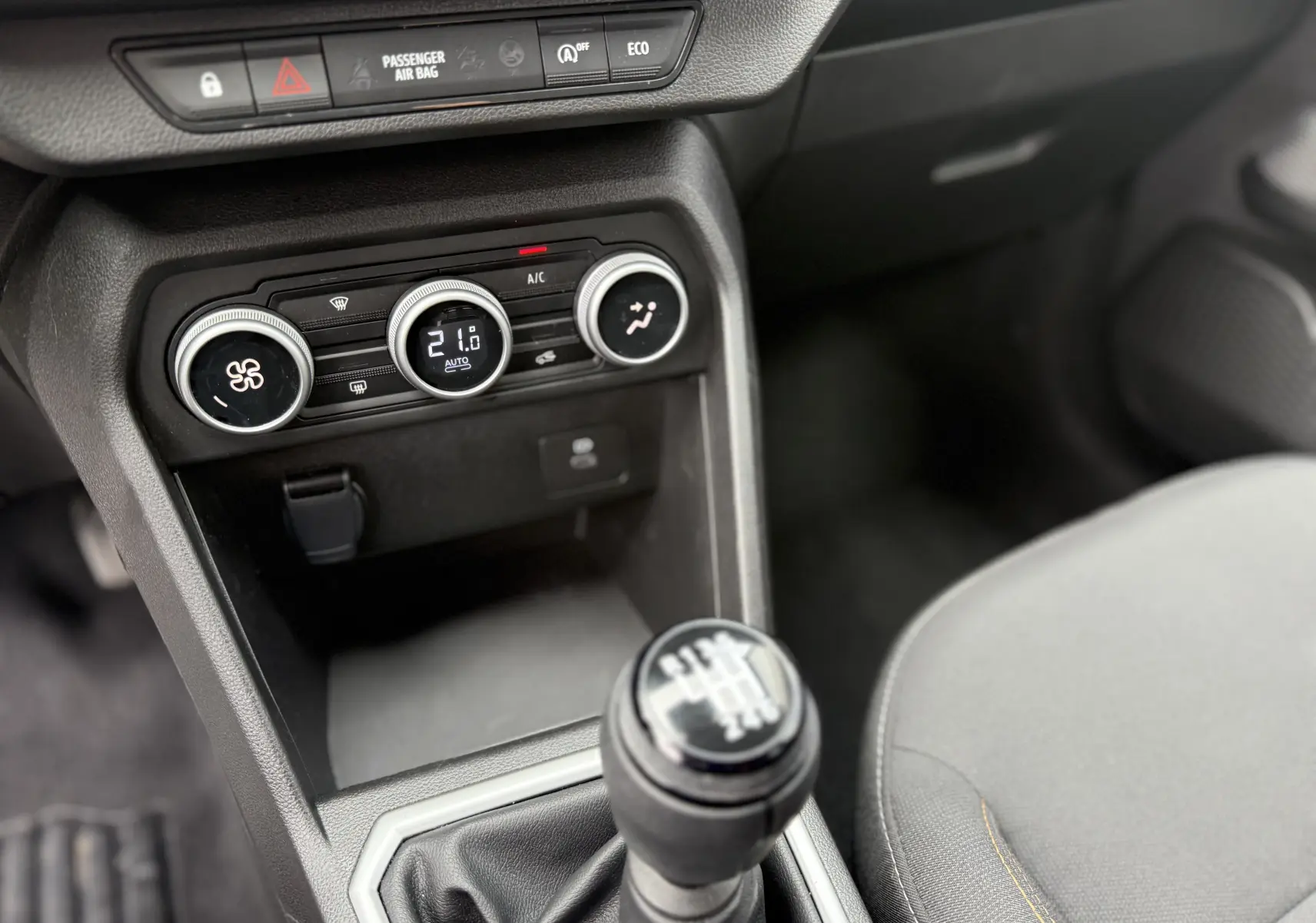 Vue intérieure centrée sur la console centrale d'une Dacia Sandero Stepway 2025, avec levier de vitesse manuel et commandes de climatisation.