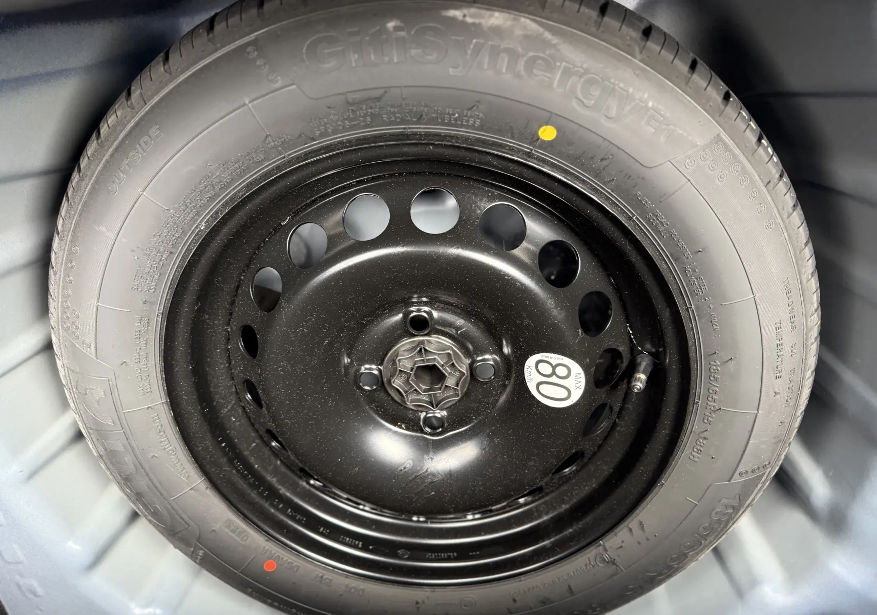 Gros plan sur la roue de secours noire montée sur un pneu GitiSynergy ET, dans le coffre d'une Dacia Sandero Stepway Bleu Iron 2025.