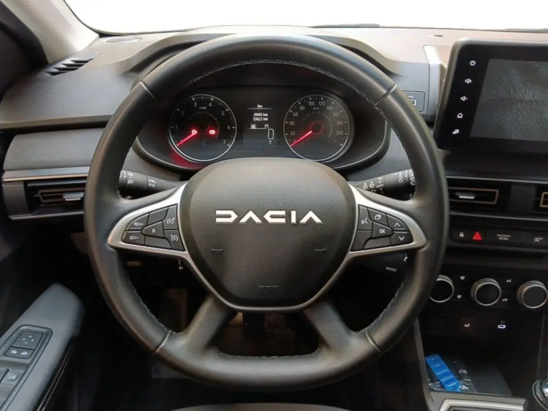 Vue centrée sur le volant noir du Dacia Sandero Stepway 2025, avec tableau de bord et écran tactile visibles.