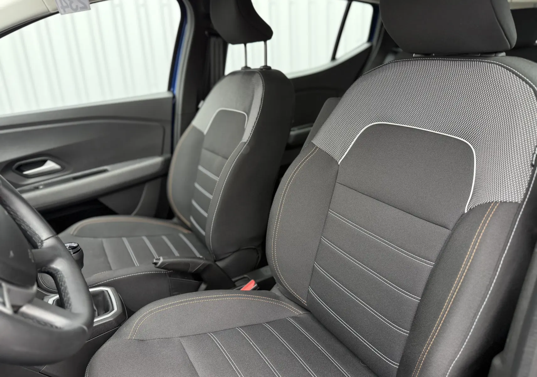 Vue intérieure rapprochée des sièges avant gris avec surpiqûres contrastantes de la Dacia Sandero Stepway Bleu Iron.