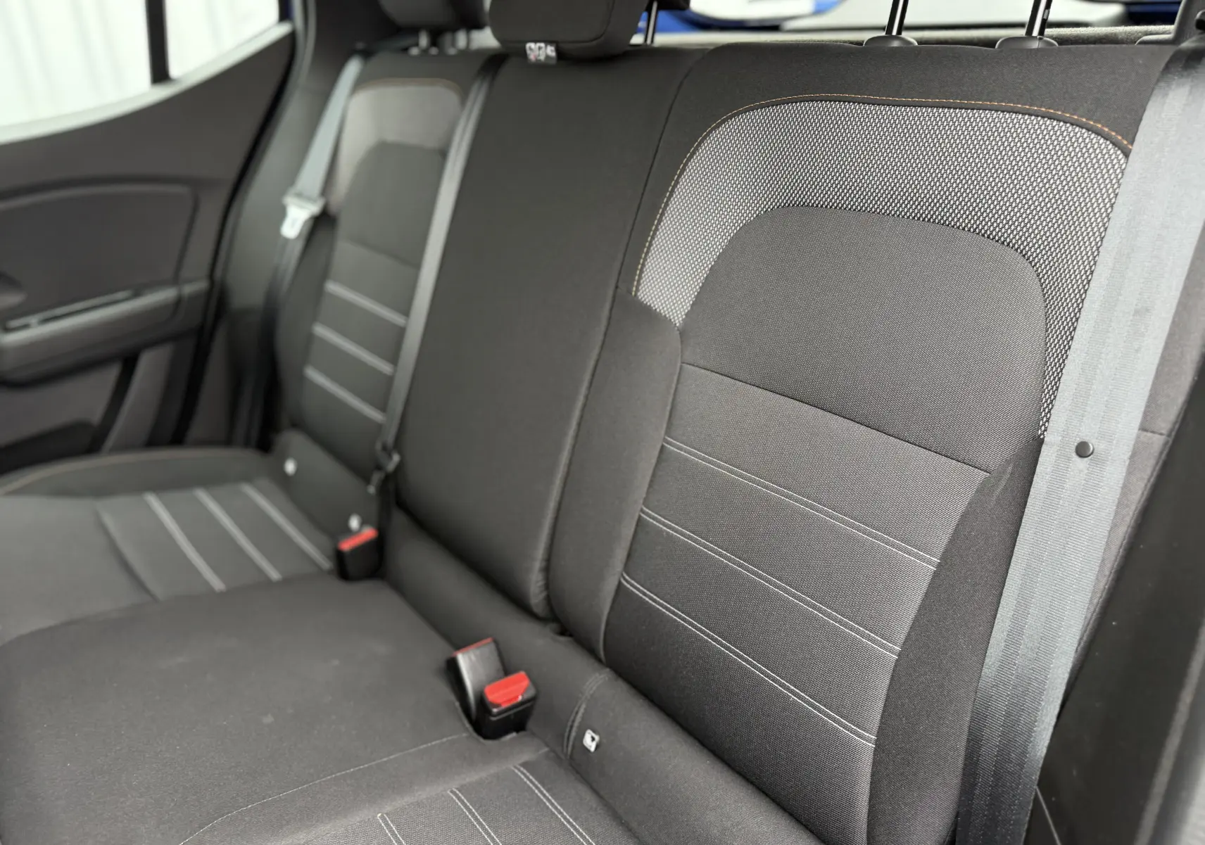 Vue intérieure des sièges arrière noirs avec surpiqûres grises du Dacia Sandero Stepway 2025, côté gauche visible.