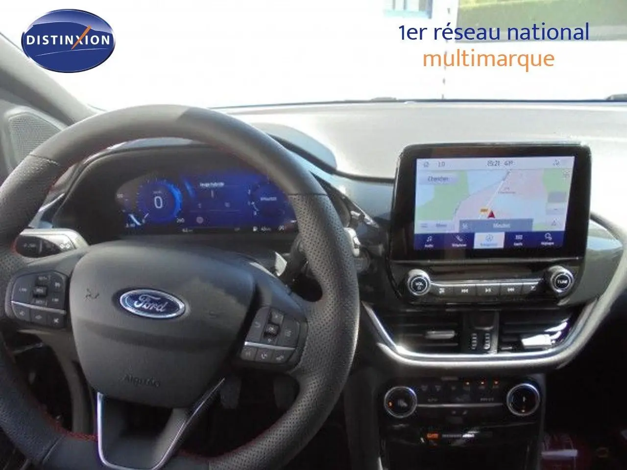 Vue intérieure du tableau de bord et volant noir perforé d'une Ford Puma 2022 avec écran tactile affichant la navigation GPS.