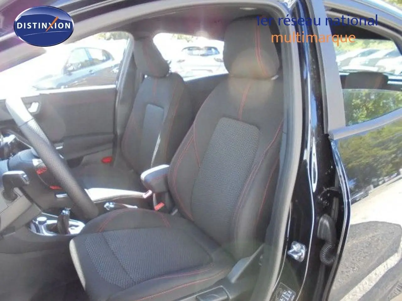 Vue intérieure côté conducteur du Ford Puma noir agate métal 2022, sièges tissu noir avec surpiqûres rouges visibles.