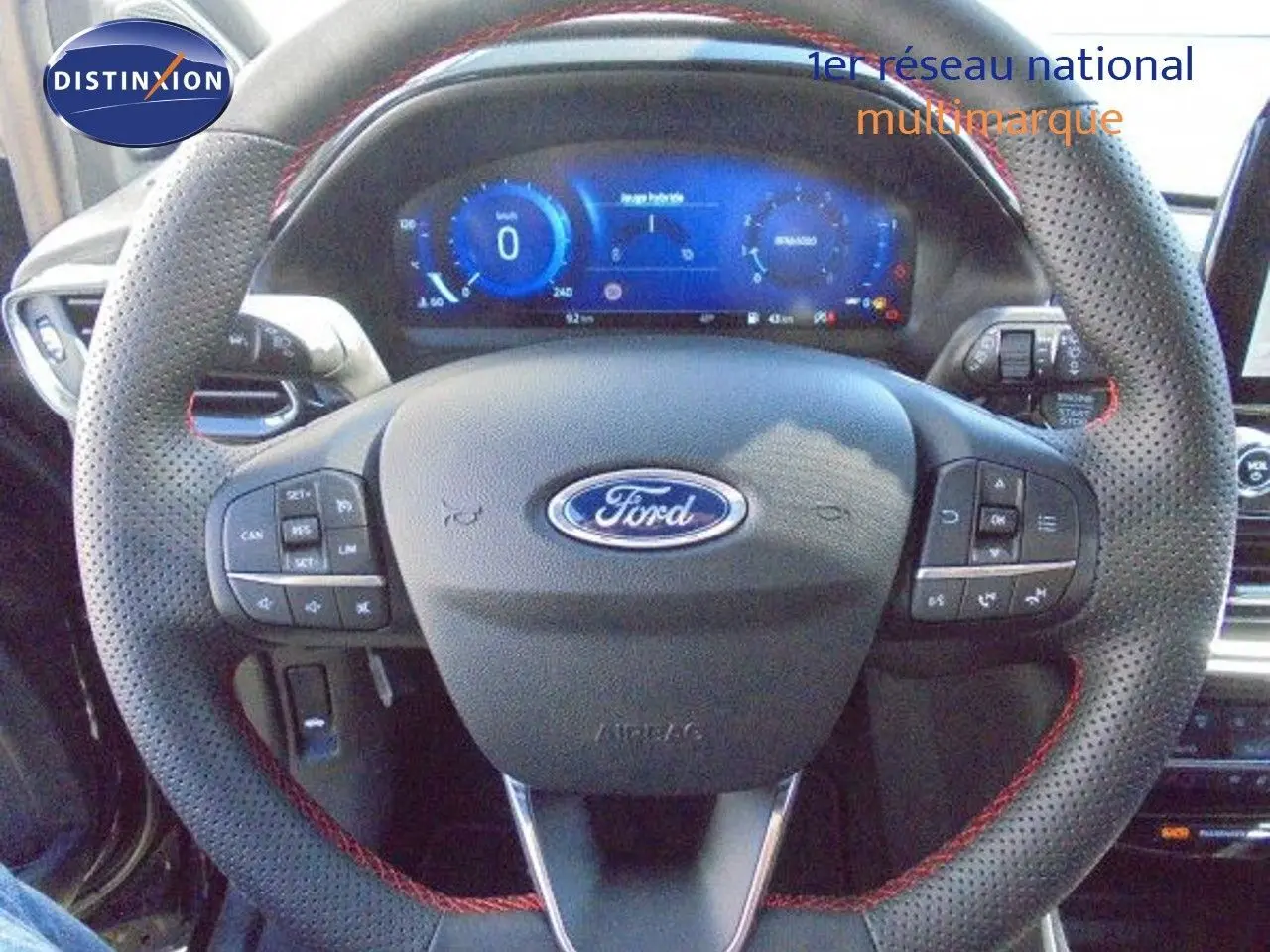 Volant perforé noir avec surpiqûres rouges et commandes intégrées, tableau de bord numérique de la Ford Puma 2022.